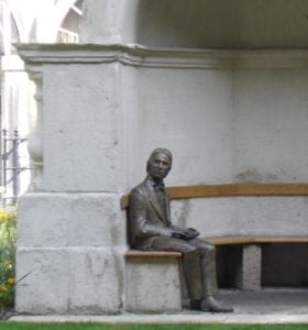 Bronze statue of John Keats, seated on a bench and looking out from the bench's alcove