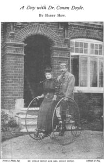 Couple on tall tricycle with the large wheels and a place where the Mrs. rides standing in front