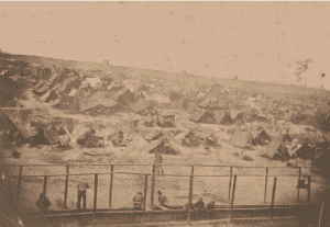 United States Civil War: Andersonville prison. "Photograph shows prisoners using latrines in the foreground, masses of huts made of sticks and blankets, and a stockade with sentry boxes in the distance (Source: Notes by Sergeant Warren L. Goss of Co. H, 2nd Massachusetts Heavy Artillery Regiment, prisoner who aided the photographer at Gilder Lehrman Institute of American History. Goss, Warren (fl. ca. 1864-1880). Descriptions of A. J. Riddle's photographs)."