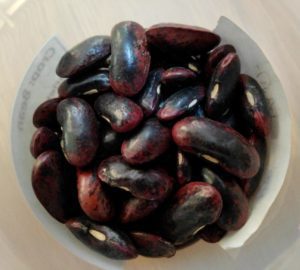 Top down view of dark reddish black beans in a cup