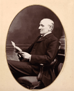 Herbert William Page seated facing left reading. Photo for article on railway spine