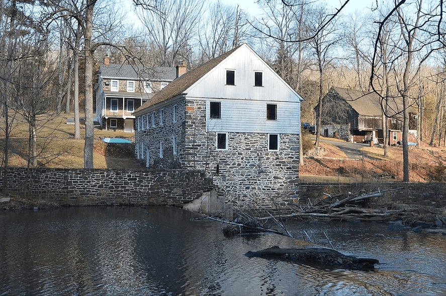 Brick house with siding in wooded area next to water