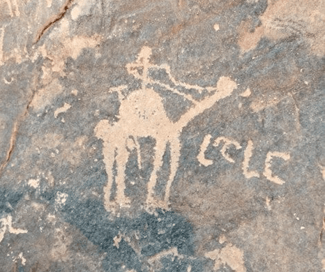 Stick figure with tool(?) riding camel, with writing