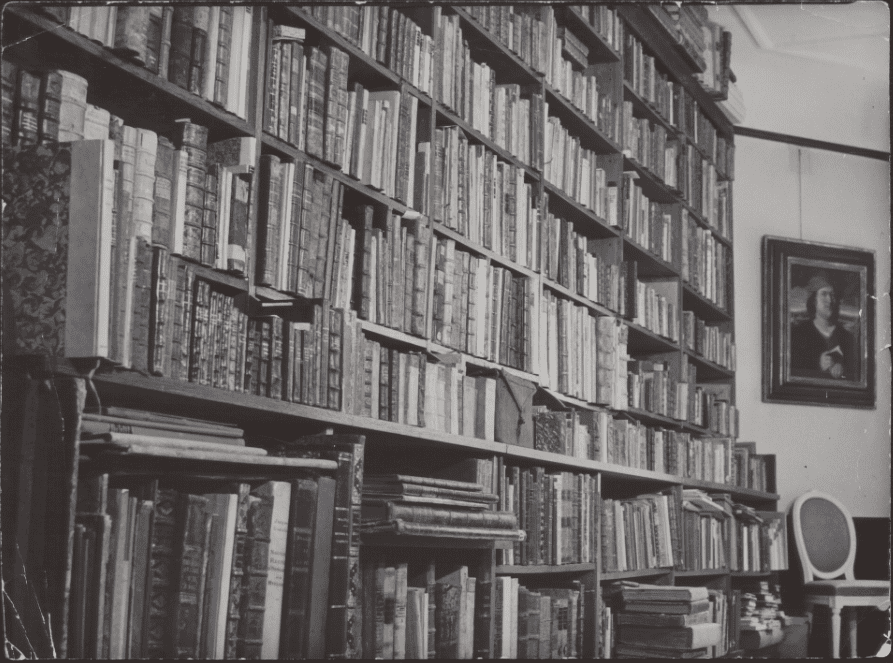 A closer view of bookshelves with a portrait of Paracelsus on the wall and a chair beneath it in Erik Waller's library