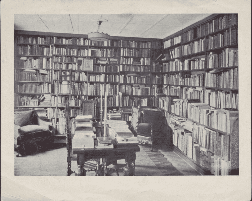 Erik Waller's library, a room with two cozy chairs and walls lined with bookcases seven or eight rows high. A table in the center of the room is covered with books and bears two tall candlesticks.