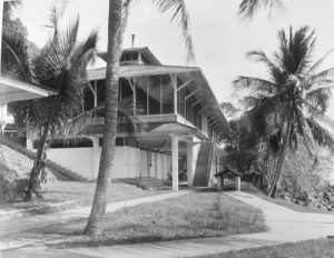 Building with awnings and large windows, surrounded by palm trees