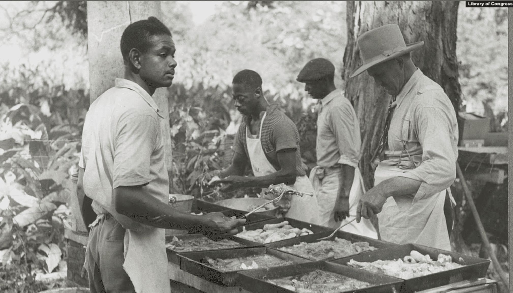 Three black men and a white man cooking outdoors