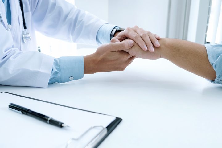 Doctor shaking both hands with a patient